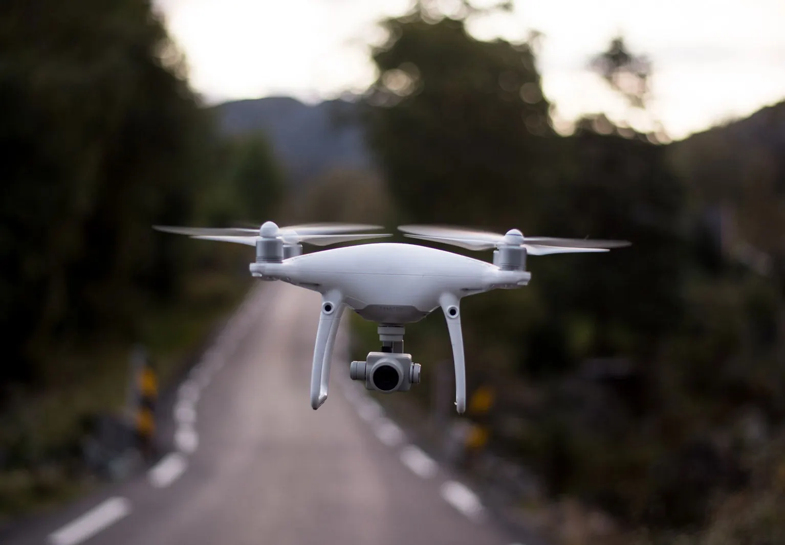 A camera drone hovering over a rural road