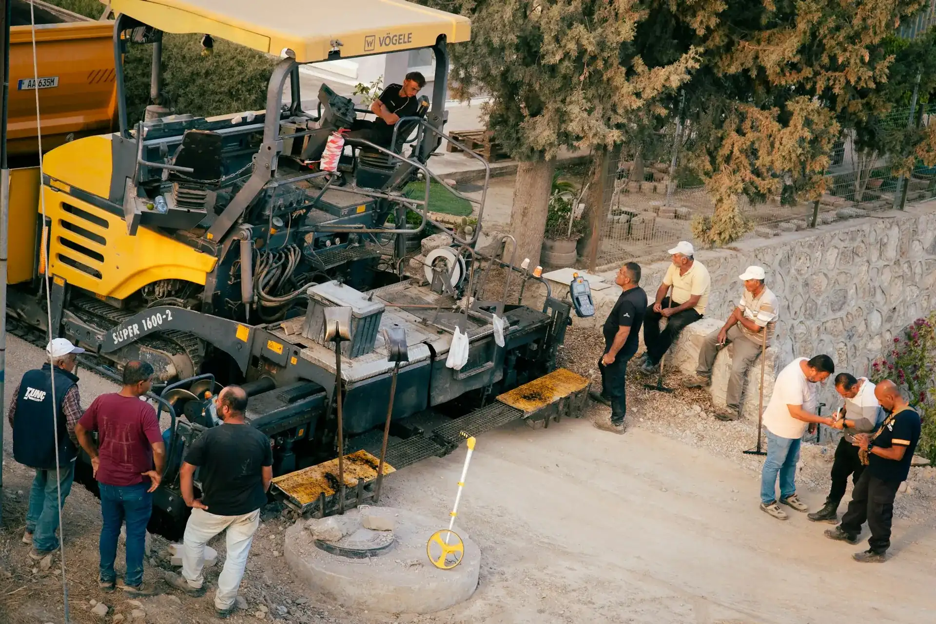 A road crew gathered around an asphalt paver on a job site