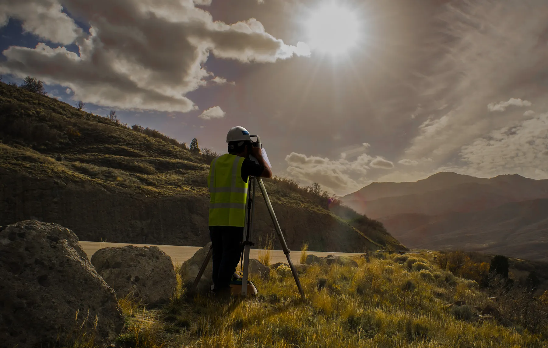 A surveyor operating equipment on a hillside